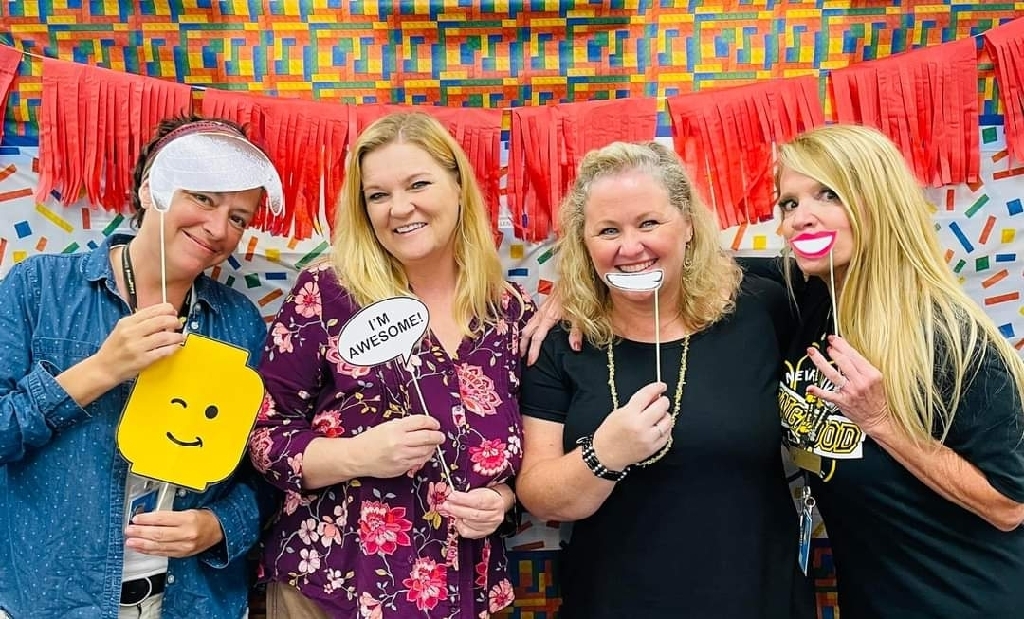 four teachers smiling with props in a photo booth