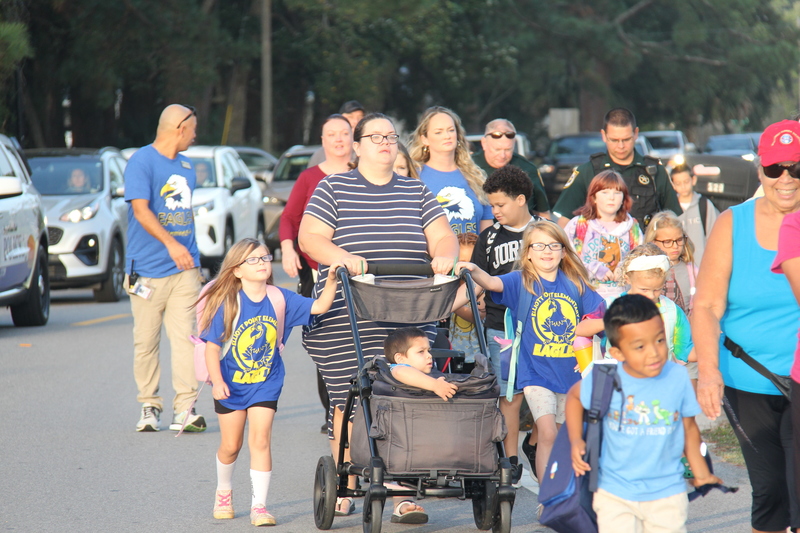 Students, families, and community members walking to school.